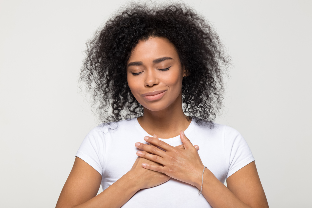 Hopeful woman with hands over her heart